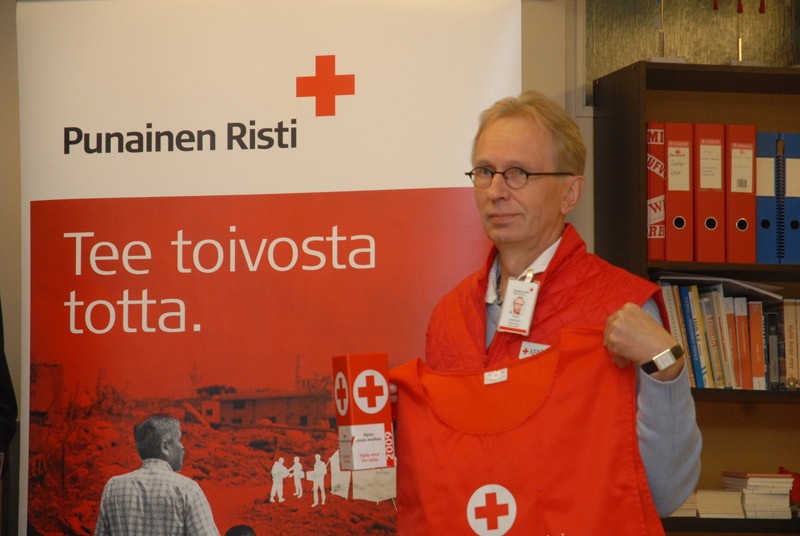 Tapio Lehtonen esittelee virallisen kerääjän tuntomerkkejä. joihin kuuluvat liivi, tietynlainen nimilappu ja lipas.