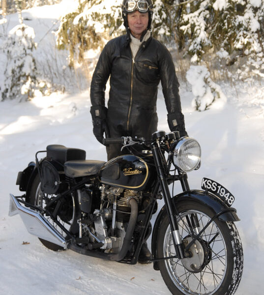 Asiallisesti sonnustautunut Jukka Helkama ja musta 350 -kuutioinen Velocette -kaunotar vuodelta 1948