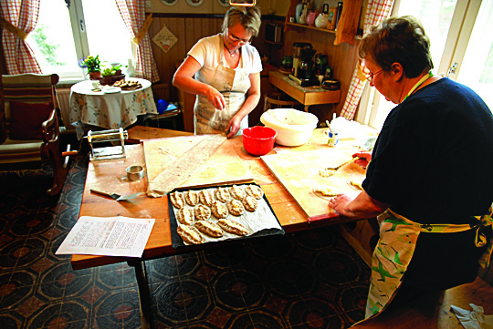 Virva Niittynen ja Riitta Varemäki työn touhussa: piirakankuoret tehdään kätevästi pastakoneella. Täyttö ja rypytys ei montaa hetkeä vie.