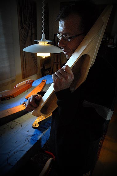 Simo Suni rapsuttaa tekeillä olevan kanteleen koverrusta sormella ja kuuntelee ääntä toiselta puolelta. Jos rapsutuksen ääni kuuluu tasaisesti joka kohtaa raaputtaessa, voi odottaa kanteleen sointiominaisuuksien olevan hyvät.