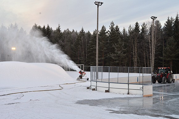 Talvi tuli Melassuolle: lumitykki puhkuu lunta ja kaukalossa Kimmo Flink huoltaa jäätä.