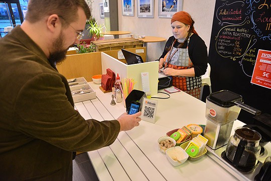 Kahvikupin voi lunastaa näinkin: Sami Lappalainen maksaa ostoksensa bitcoineilla. Sari Kippilä näkee summan siirtyvän kassaan siinä, missä käteis- tai korttimaksullakin.