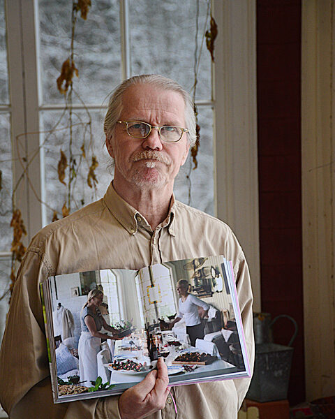 Timo Viljakainen on ehtinyt kuvata monenlaista. Viljakainen pitelee Lauantaina lautasella-kirjaa, johon hän otti kuvan Särkisalon Meritorpan kuistille katetusta juhlapöydästä.