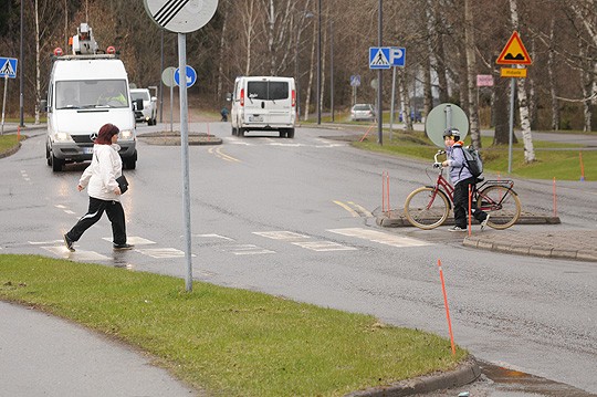 Mallisuoritus; valkoinen pakettiauto jarruttaa, sillä suojatielle on astumassa kaksi jalankulkijaa. Jos pyöräilijä tulisi paikalle polkien, hän olisi väistämisvelvollinen.