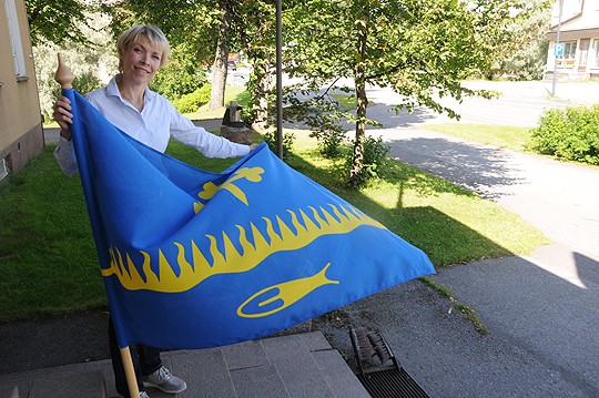 Uusikirkko-seuran lippu viittaa muun muassa maanviljelykseen ja kalastukseen, kertoo Outi Grusander.