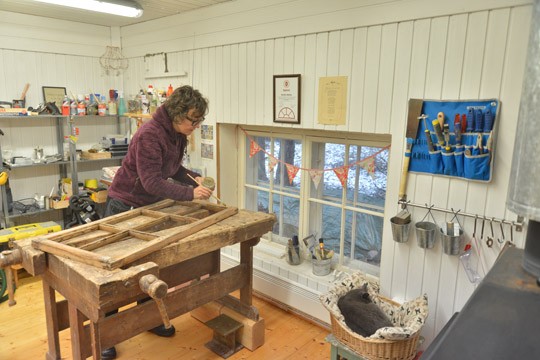 Marika Mattila levittää kittiä vanhan ikkunan karmiin. Sään salliessa työmaa voi siirtyä myös pihalle.