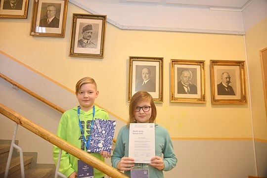 Joel Engblom ja Anni Laitinen lähtevät Särkisalosta juhlistamaan itsenäisyyttä Säätytalolle. Koulun käytävältä lähtijöitä katsoo presidenttien rivi.