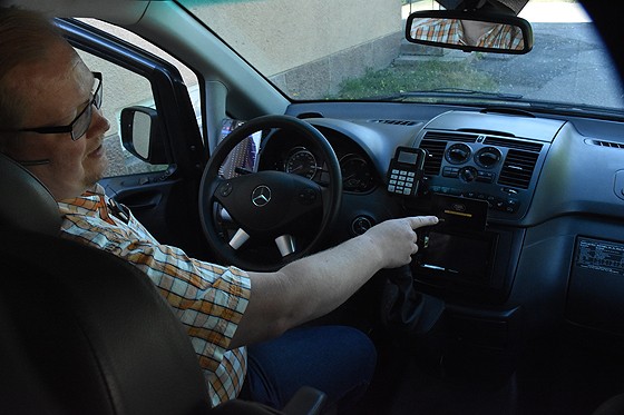 Taksin ohjaamossa on monenlaista lisävarustetta, ja yhden niistä vaatii Kela-kyytien välityskeskus: Juha-Pekka Honkanen näyttää vaatimuksen mukaista taksamittaria.