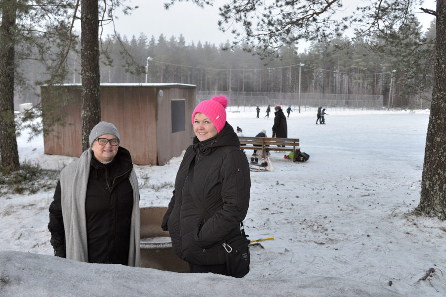 Kaksi naista, taustalla luistelukenttä ja luistelijoita.