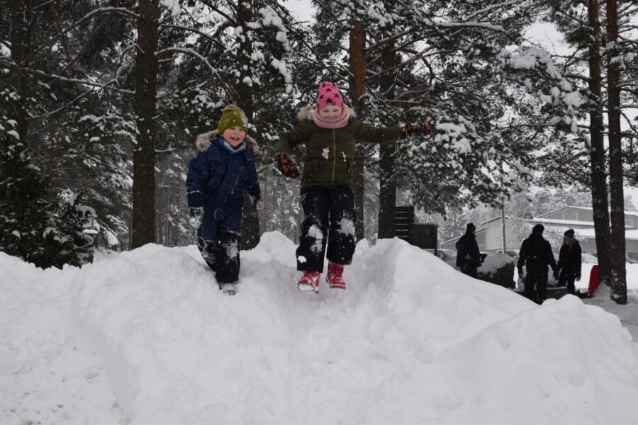 Frida ja Ronny Holm hyppivät kilpaa lumikasassa.