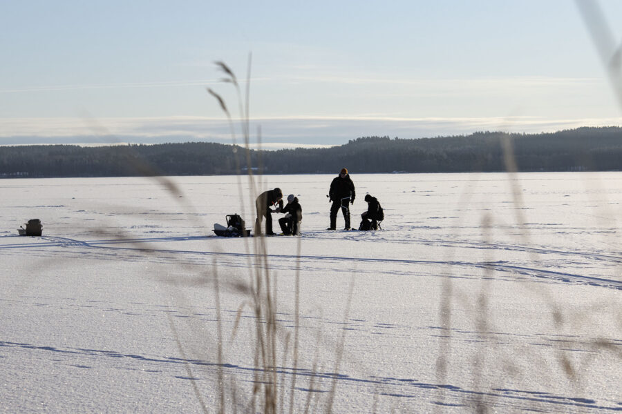 Kuva talviselta meren jäältä, jossa näkyy pilkkijöitä.