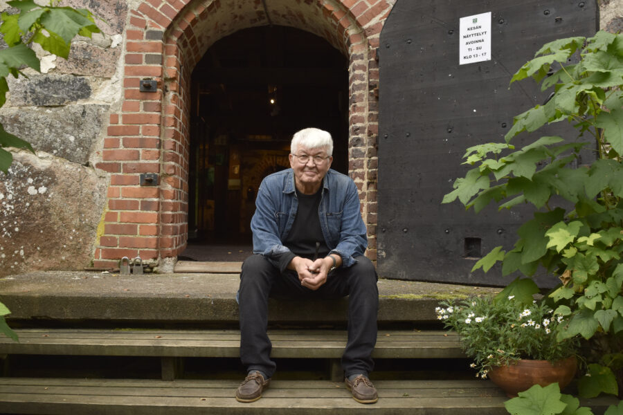 Mies istuu portailla ja katsoo kameraan.