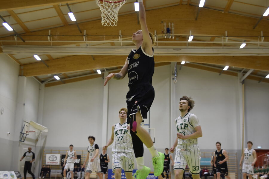 Patrik Poutianen nostaa pallon koriin puolustajien edestä.