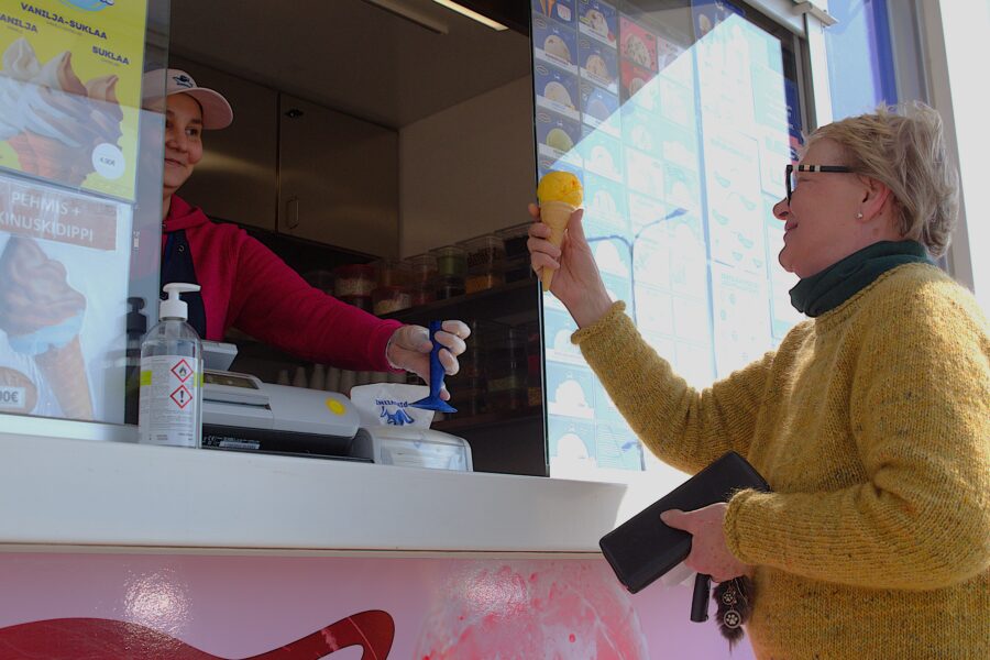 Myyjä ojentaa asiakkaalle jäätelön.