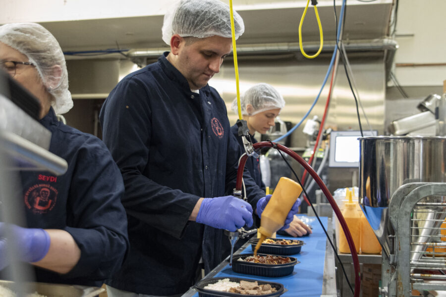 Työntekijöitä valmistamassa liukuhihnalla kebabannoksia.