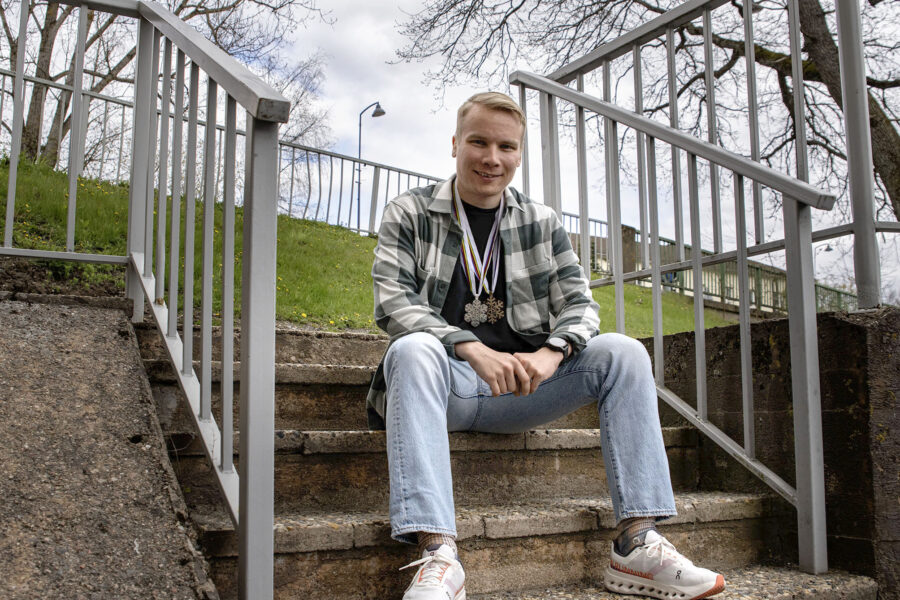 Lauri Vuorinen istuu portailla. Hänellä on kaulassaan kaksi mitalia.