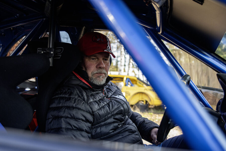 Mies istuu ralliauton kuljettajan penkillä.