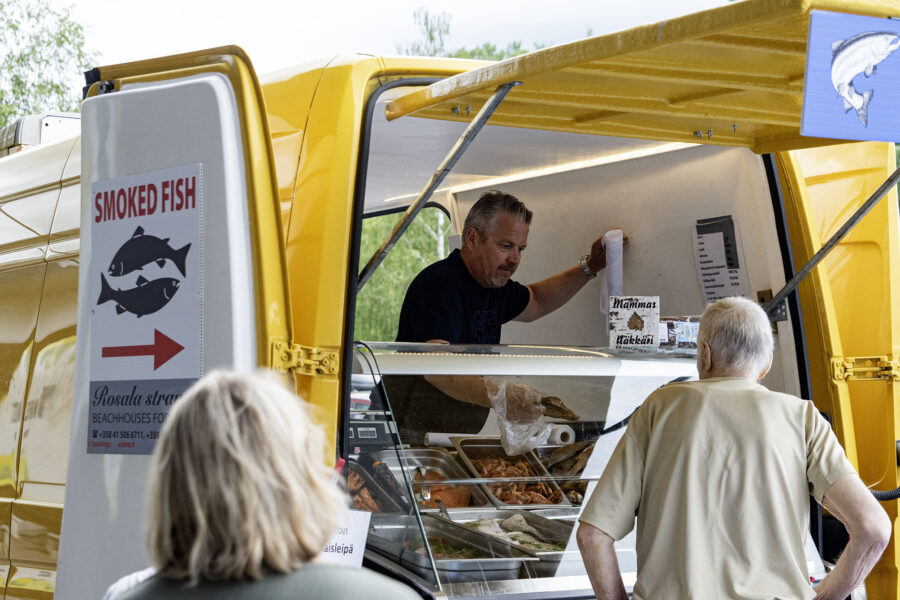 Asiakkaita ostamassa kalaa pakettiauton takakontista.