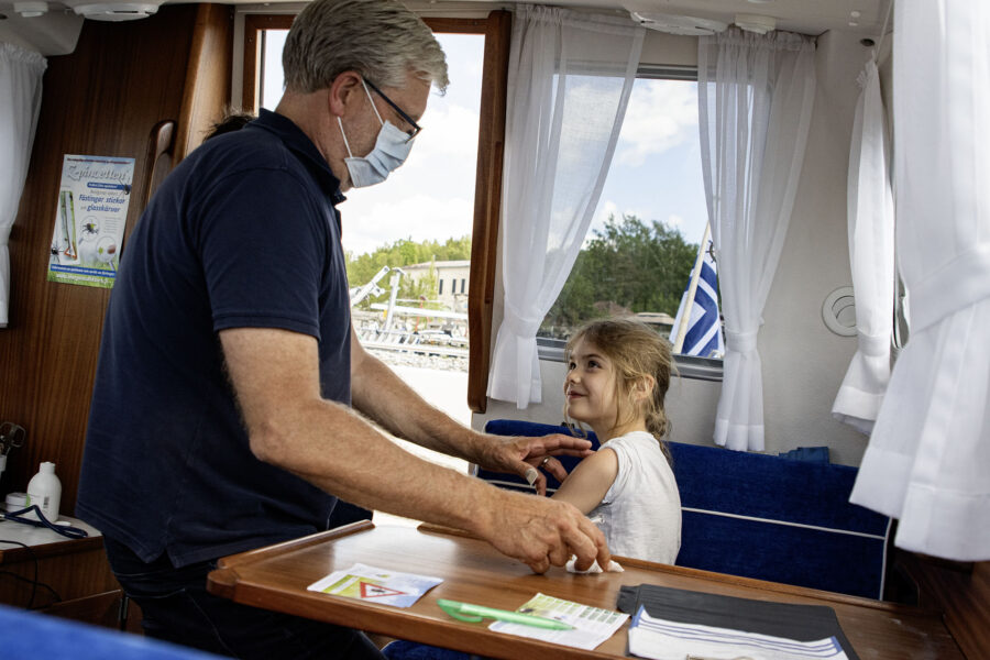 Lääkäri antaa rokotetta lapselle veneessä.