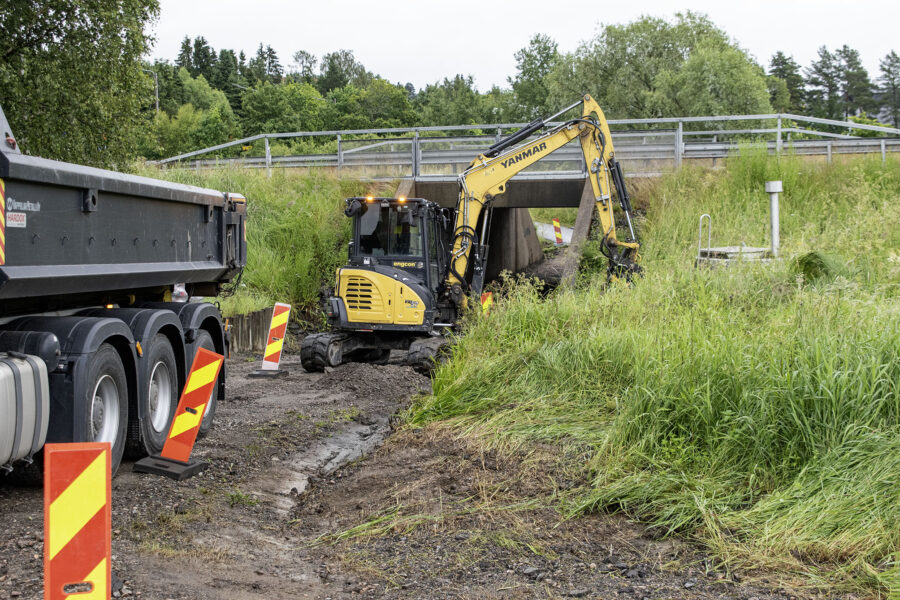 Kuvassa kaivuri ja rekka-auto alikulkutunnelin edessä.